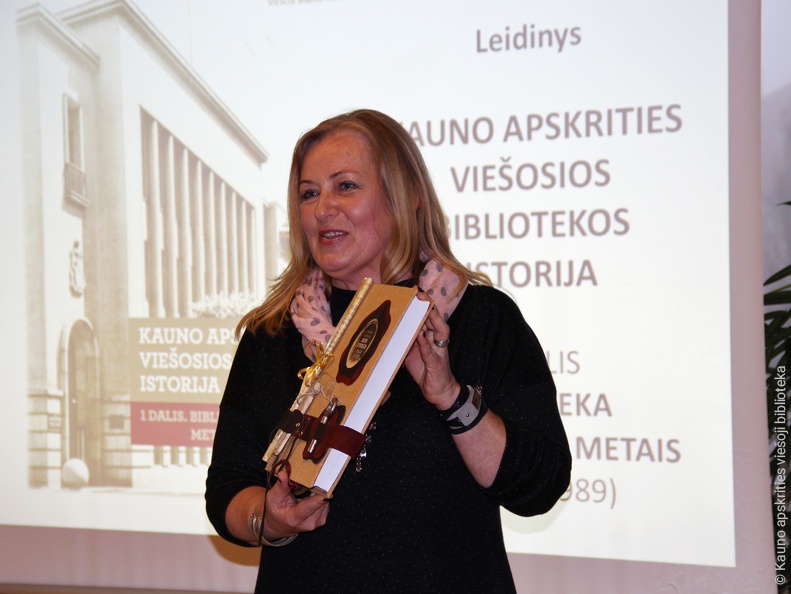 R. Tamoliūnienė laiko rankų darbo bibliotekos istorijos leidinį